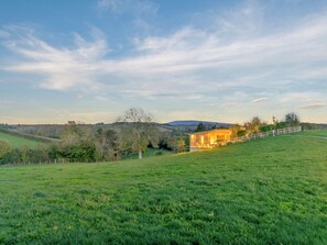 A rural landscape with a house on a hill, surrounded by green fields and trees. - 1 bedroom accommodation in Malvern (Malvern)