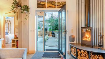 A cozy living room with a fireplace, a glass door leading to a patio, and a small dog.