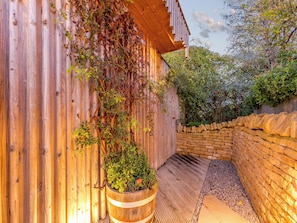 Un bâtiment en bois avec un mur en pierre et un jardinier en forme de tonneau en bois.