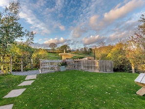 A garden with a wooden fence, a paved pathway, and a bench.