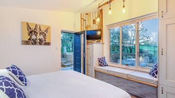 A bedroom with a bed, a bench with a TV, a large window, and a painting of donkeys.