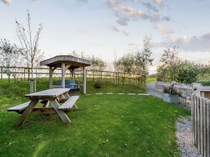 A picnic area with a wooden table and benches, a gazebo, and a fenced garden. - 1 bedroom accommodation in Malvern (Malvern)