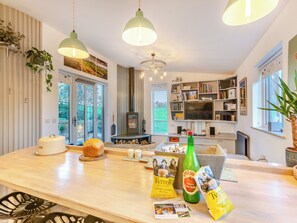 A modern kitchen with a central island, pendant lighting, a built-in fireplace, and a large window offering a view of the outdoors.