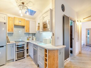 A modern kitchen with a skylight, built-in appliances, and wooden cabinetry.