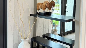 Et moderne interiør med en hvid vase, trægrene og en sort bænk.