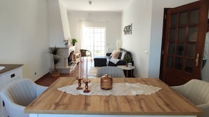 A dining area with a wooden table, white chairs, and pendant lighting. - Casa das Rosas- Villa with garden, Charneca da Cotovia (Charneca da Cotovia)
