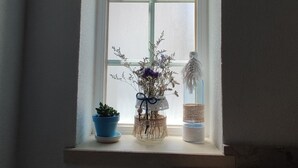 A window with frosted glass panes, a small shelf with a potted plant, a decorative vase, and a woven basket. - Casa das Rosas- Villa with garden, Charneca da Cotovia (Charneca da Cotovia)