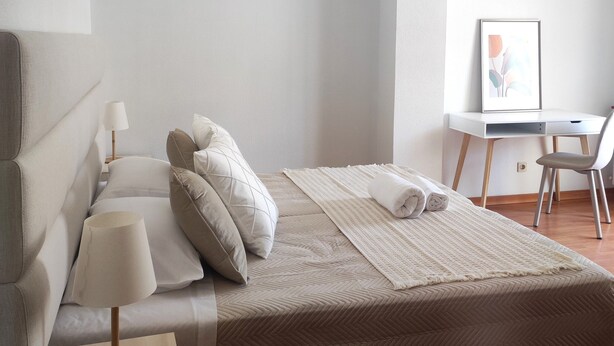 A modern bedroom with a bed, bedside table, lamp, and a desk with a chair. - Casa das Rosas- Villa with garden, Charneca da Cotovia (Charneca da Cotovia)