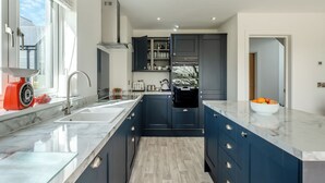 Una cocina moderna con armarios oscuros, encimera de mármol y un amplio ventanal.
