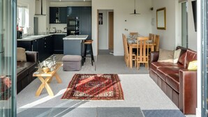 Una cocina moderna con armarios oscuros, una isla central y una zona de comedor con mesa y sillas de madera.