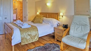 A hotel room with a bed, a chair, a nightstand, and a wooden floor.