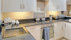 A modern kitchen with white cabinets, a stainless steel sink, and a toaster.
