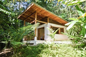 A wooden-roofed building surrounded by dense tropical foliage.