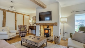 A living room with a fireplace, a flat-screen TV, and a large window with a view. - Hares Hollow - UK33953 (Llanymynech)