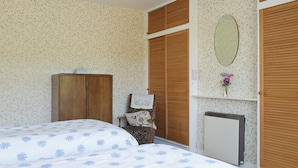Een slaapkamer met een bed, kledingkast, spiegel en radiator.
