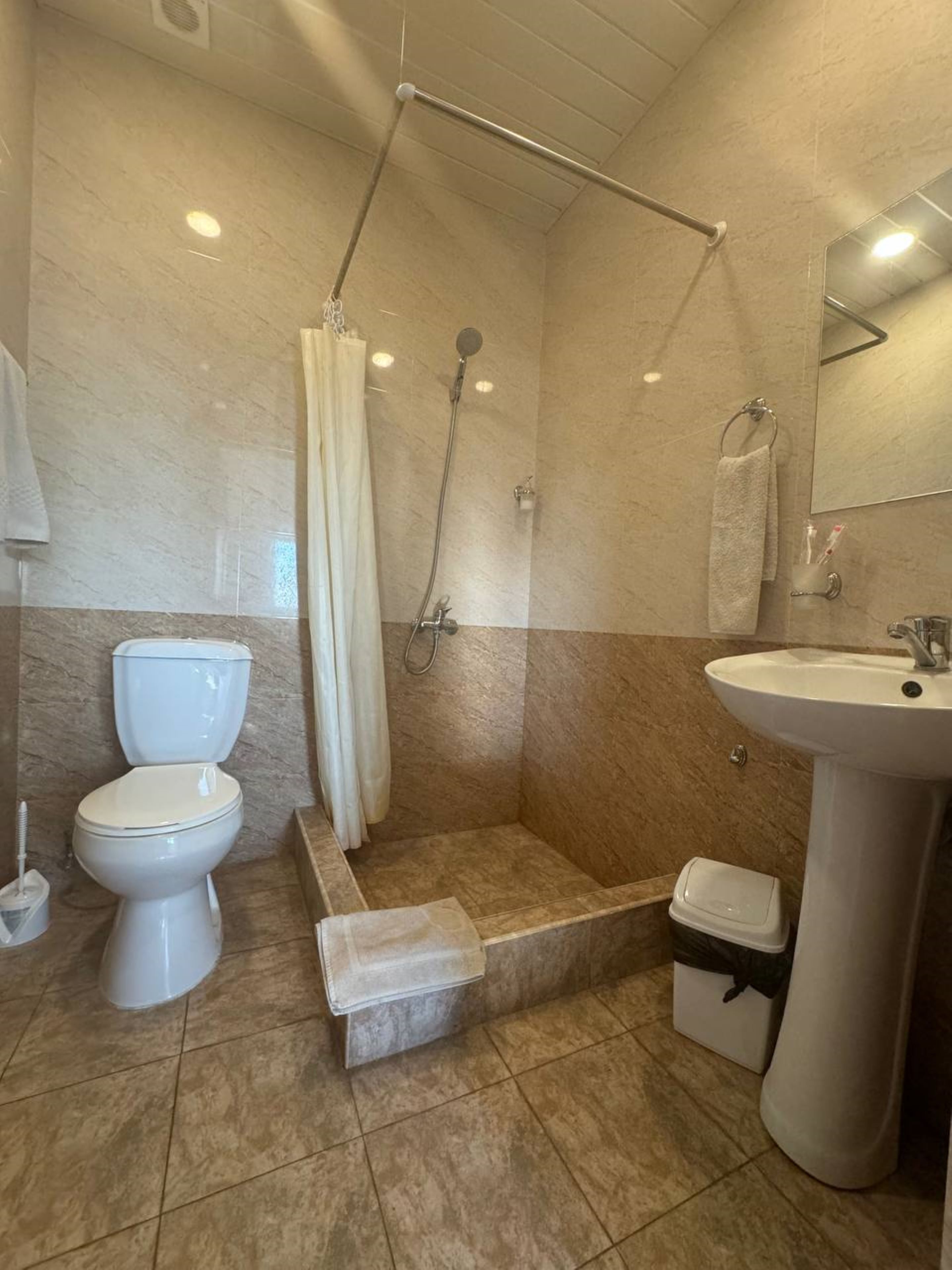 A bathroom with a shower, toilet, and sink.