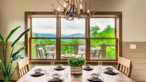A dining area with a table set for six, large windows offering a mountain view, and a chandelier.
