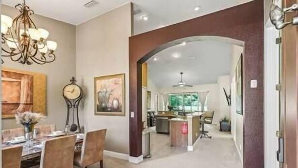 Un coin repas agrémenté d’un lustre, d’une horloge et d’un tableau au mur.