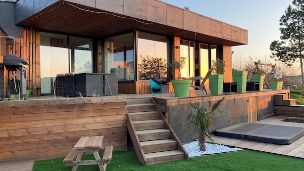 A modern house with a wooden deck, outdoor seating, and a small garden area. - Beautiful architect-designed house in the Monts du Lyonnais region (Chabanière)