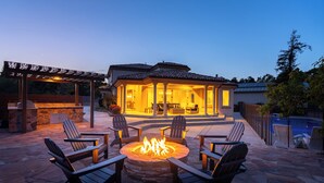 A patio area with Adirondack chairs, a fire pit, and a covered seating area. - Templeton Retreat • Pool, Spa • Near Wineries (Templeton)