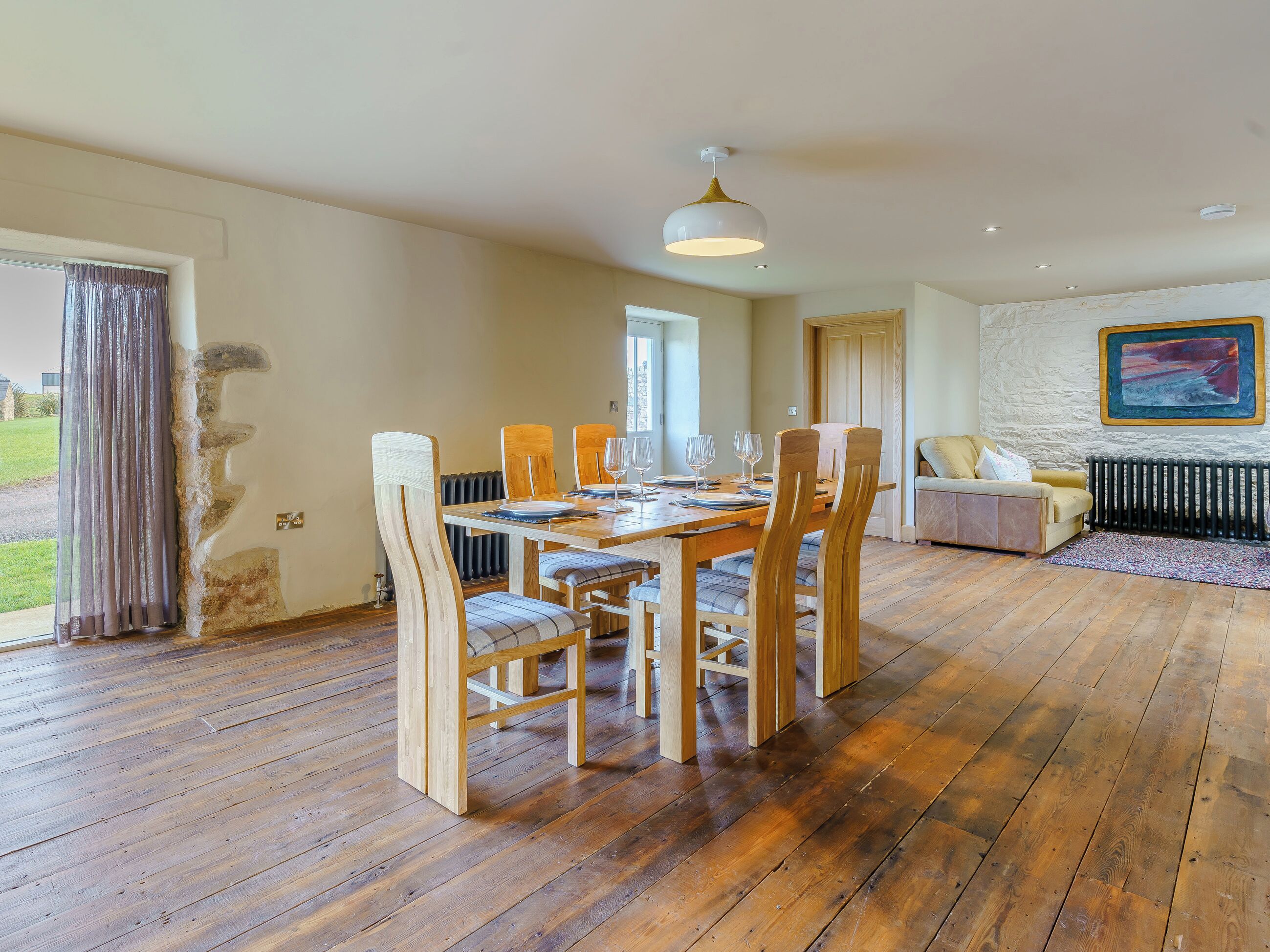 A dining area with a wooden table, chairs, and a hanging light fixture.