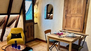 Une pièce chaleureuse avec une table en bois dressée pour le repas, un fauteuil jaune et une petite table ronde sur laquelle sont posées des boissons.