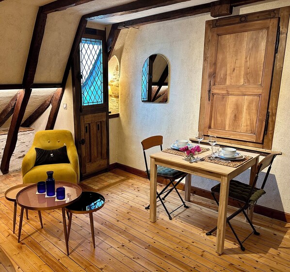 A cozy room with a wooden table set for dining, a yellow armchair, and a small round table with drinks.