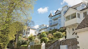 A residential street with houses, a stone wall, and a clear sky. - 3 bedroom accommodation in Kingswear (Kingswear)