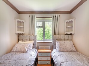 A bedroom with two beds, a window, and built-in shelving.
