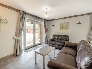 A living room with a brown leather sofa, a white table, and a sliding glass door leading outside.