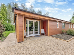 A single-story building with a covered patio area, a sliding glass door entrance, and a small outdoor seating area.
