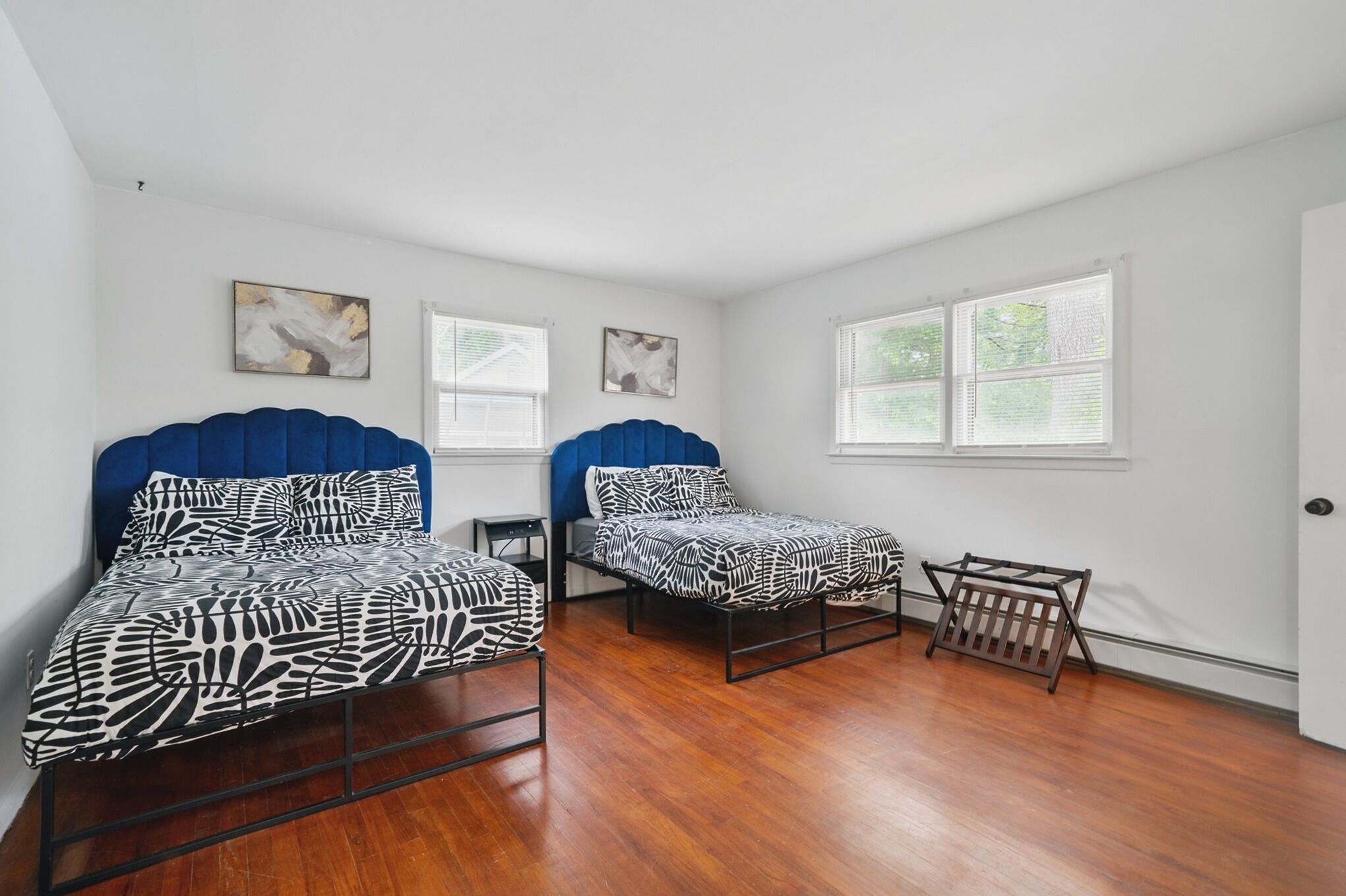 A bedroom with two beds, a small table, and a window.