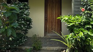 Una casa con techo de lámina corrugada, puerta de madera y un pequeño porche delantero.