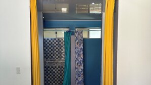 Habitación de hotel con cama, zona de ducha y vistas al exterior.