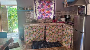 Una cocina con salpicadero de azulejos, un refrigerador de acero inoxidable y una ventana con cortina estampada.