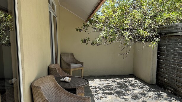 Un área de patio techada con piso estampado, un sofá de mimbre y una mesita.