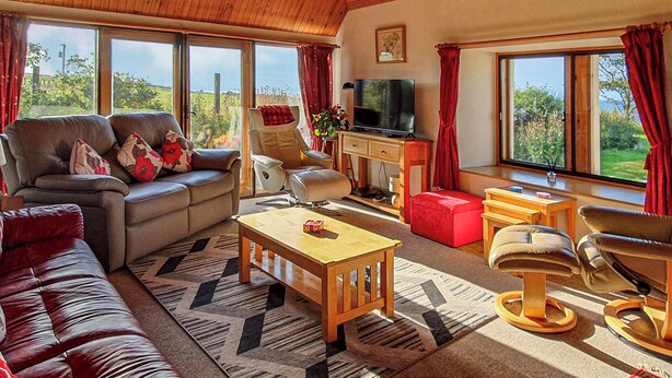 A spacious living room with a leather sofa, a wooden coffee table, and a television.