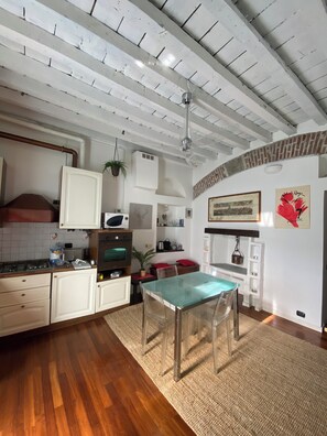 A kitchen with white cabinets, a wooden countertop, a glass table, and a hanging plant. - Cozy romantic two-room apartment St. Gotthard in Old Milan style (Milano)