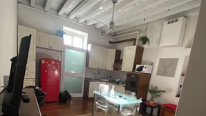 Cocina con vigas de madera, un refrigerador rojo y un comedor con sillas transparentes.