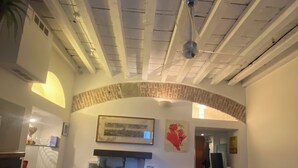 Una habitación con una mesa de vidrio, un arco de ladrillo y un ventilador de techo.