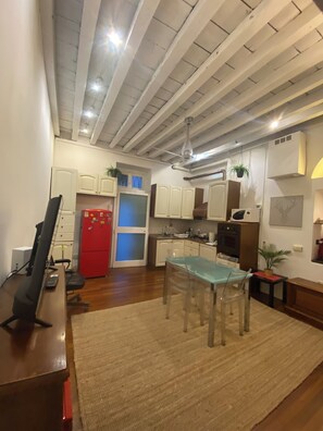 Cozy living space with a kitchenette and dining area, featuring a high ceiling with exposed beams and a dining table.