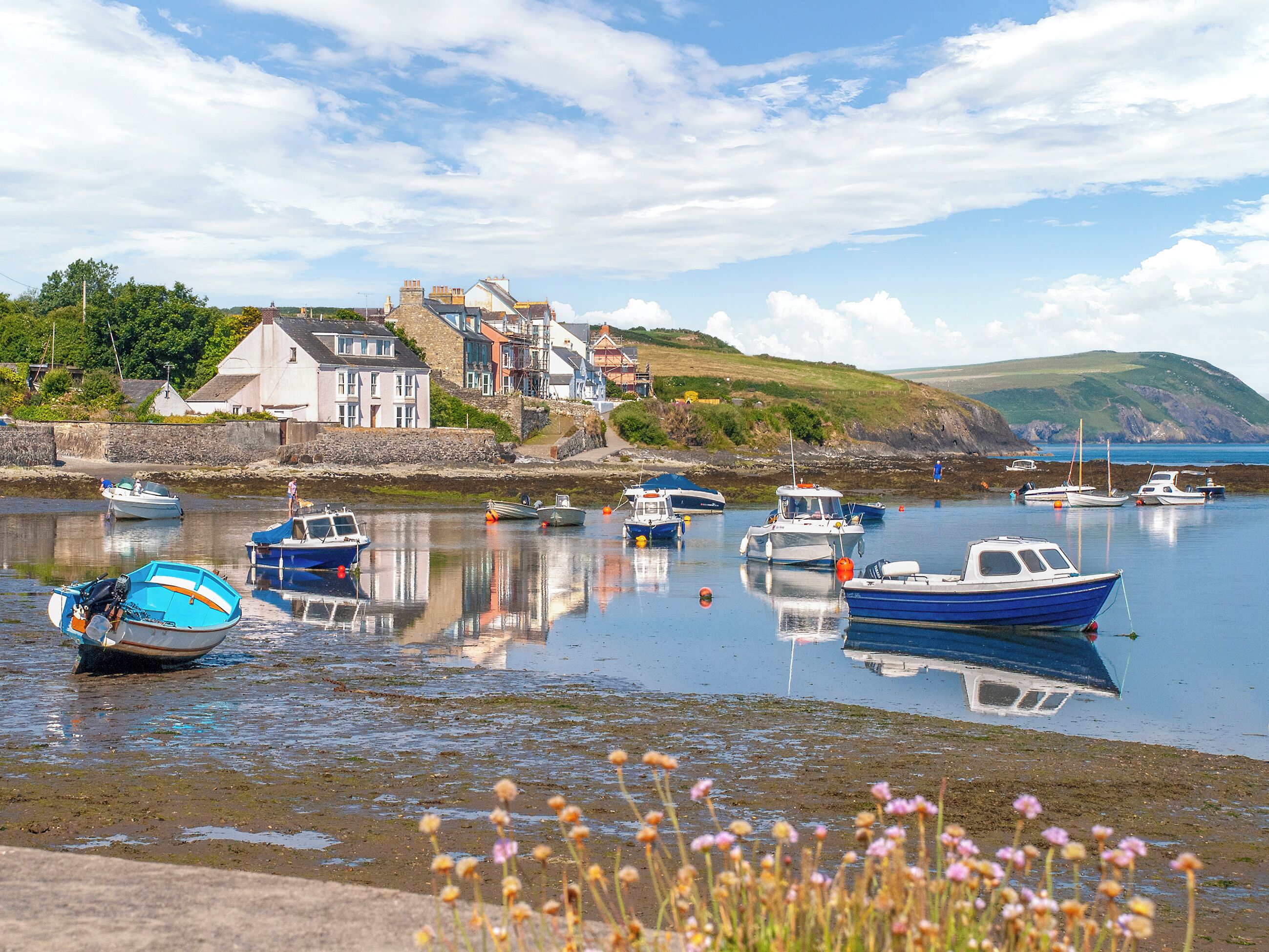 A harbor with boats, a stone wall, and buildings in the background.