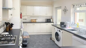 Una cocina moderna con armarios blancos, estufa a gas, microondas y lavadora.