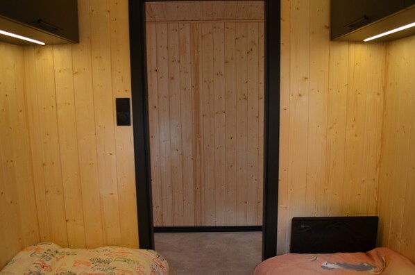 A room with wooden panel walls, a bed with a patterned bedspread, and a black headboard.