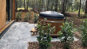 Un espacio exterior moderno con un barril de madera, un banco y una terraza.