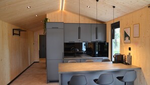 Una cocina moderna con paredes de madera, una isla central con taburetes de bar e iluminación colgante.
