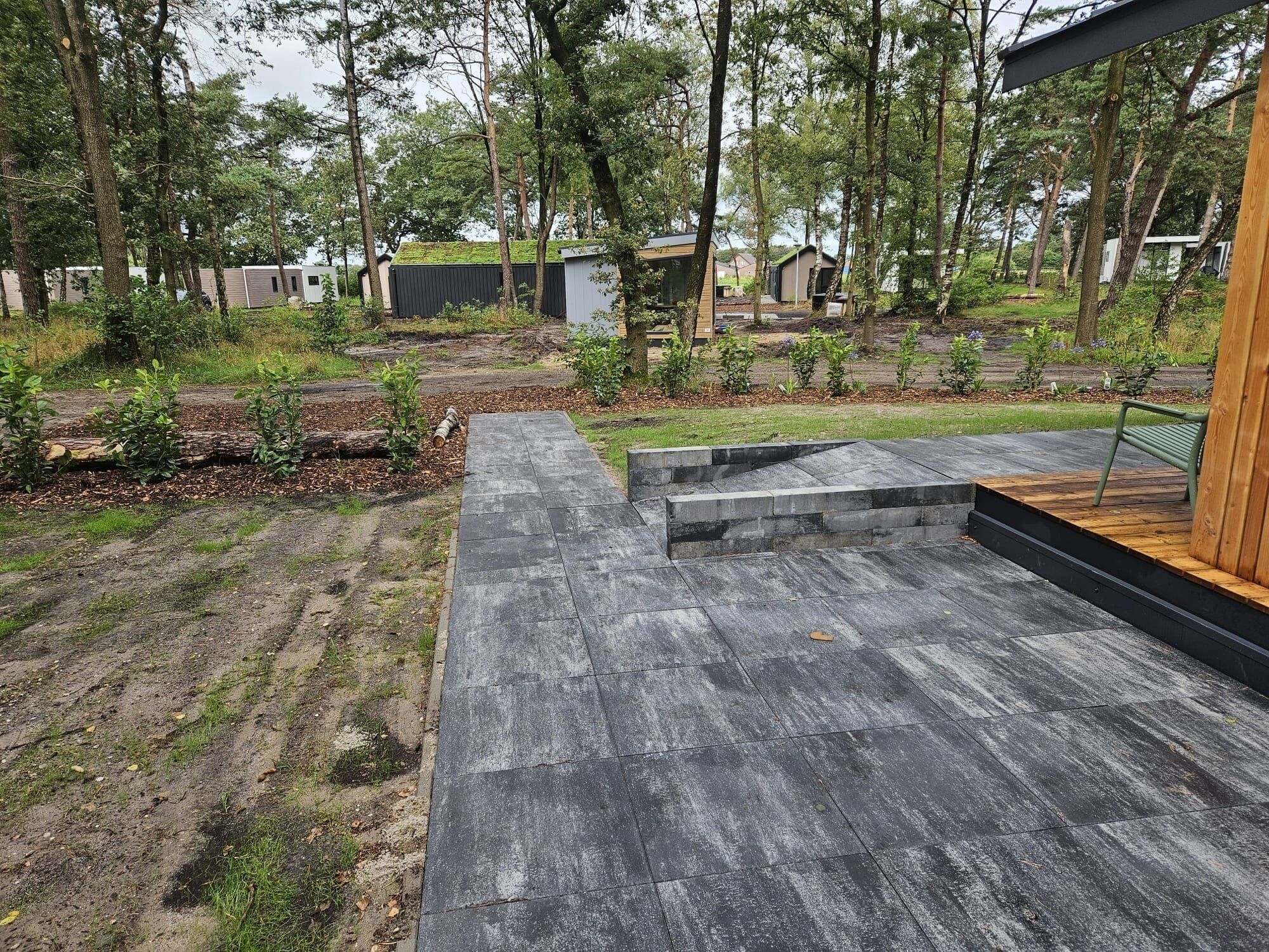 Un patio exterior moderno con suelo de hormigón y escalones de madera que conducen a una zona de estar.