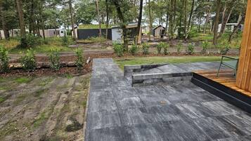 Un patio exterior moderno con suelo de hormigón y escalones de madera que conducen a una zona de estar.