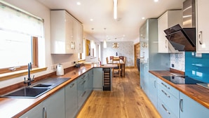 A modern kitchen with wooden countertops, grey cabinets, and a dining area with a wooden table and chairs.