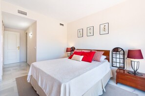 A bedroom with a bed, bedside tables, and wall-mounted artwork.
